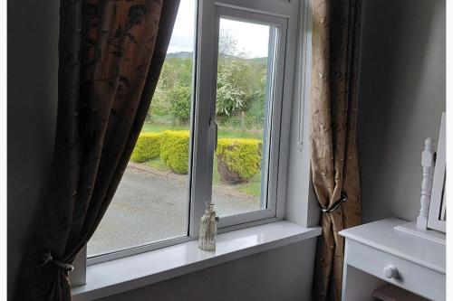 a window with a bottle sitting on a window sill at Cottage - Sleeps 6 - Parking in Letterkenny