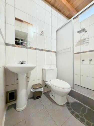 a white bathroom with a sink and a toilet at Hostal Catequil in Cajamarca