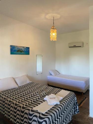 a bedroom with two beds and a chandelier at Pousada Kalangoo in Barra Grande