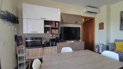 a living room with a table and a kitchen with a tv at Il Tramonto in Elmas
