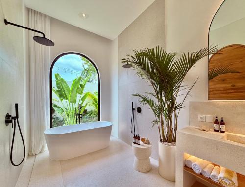 a bathroom with a tub and a palm tree at Dolce x The Young Villas in Uluwatu