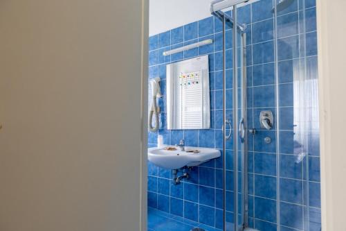 a blue tiled bathroom with a sink and a shower at Little Garden in Formia
