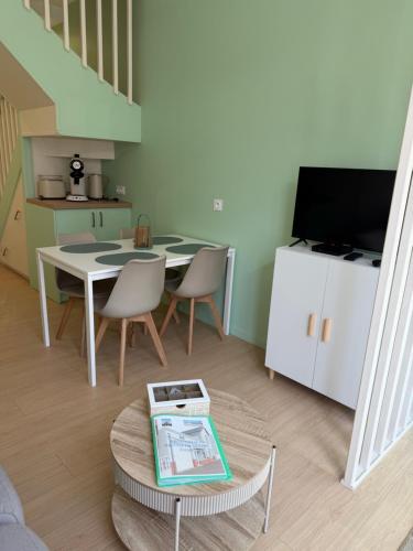 a living room with a table and chairs and a television at Le refuge de Notre-Dame in Berck-sur-Mer