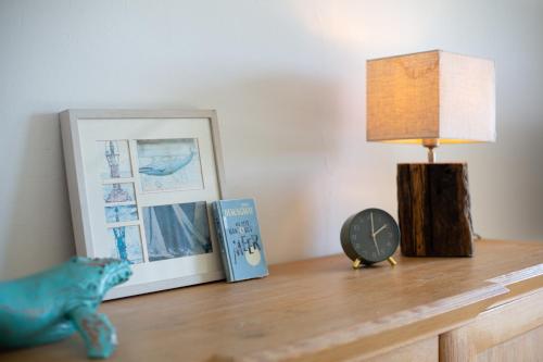 a lamp on a table with a picture and a clock at Ferienhaus Marienleuchte in Marienleuchte
