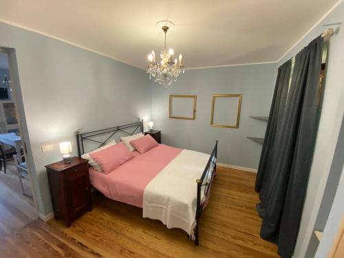 a bedroom with a bed with pink sheets and a chandelier at Cascina Vica Biella in Andorno Micca