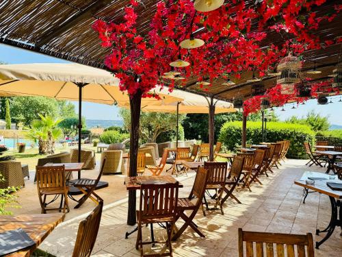 a patio with tables and chairs and red flowers at CÉRÈS - Boutique-Hôtel & Spa - Élégance en Terre d'Uzès in Saint-Quentin-la-Poterie