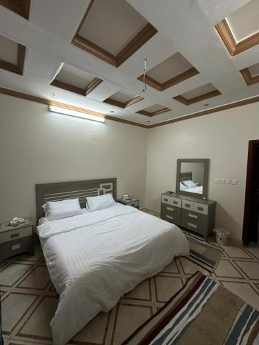 a bedroom with a large white bed and two night stands at شقة واسعة بحي الدوحة لـ 10 أشخاص 6دقائق للبحر in Yanbu