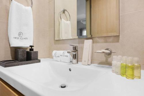 a bathroom with a white sink and a mirror at FIRST CLASS 1BR Cozy Luxury Retreat in ‘Ūd al Bayḑāʼ