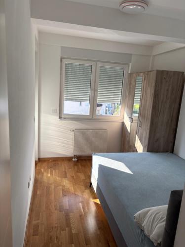 a bedroom with a bed and two windows at Modern Apartment Laktaši in Laktaši