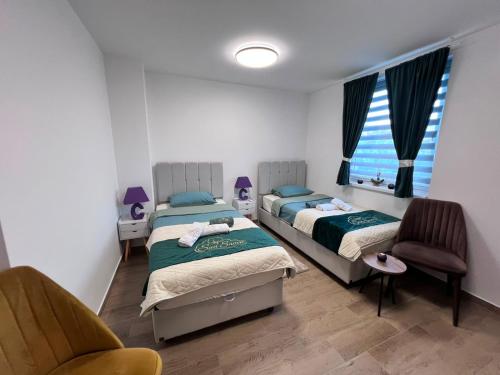 a bedroom with two beds and a chair and a window at Apartmani San Snova in Kotor-Varoš