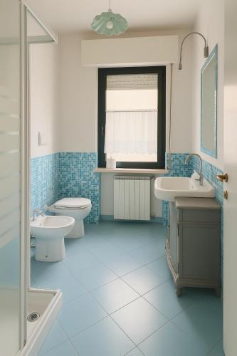 a blue bathroom with two sinks and a toilet at art apartament cerea in Cerea