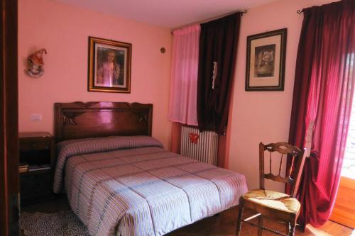 a bedroom with pink walls and a bed and a chair at Rooms Alpe Veglia-Varzo in Varzo