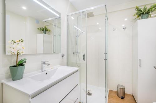 a white bathroom with a sink and a shower at Jardins Vale de Parra in Albufeira
