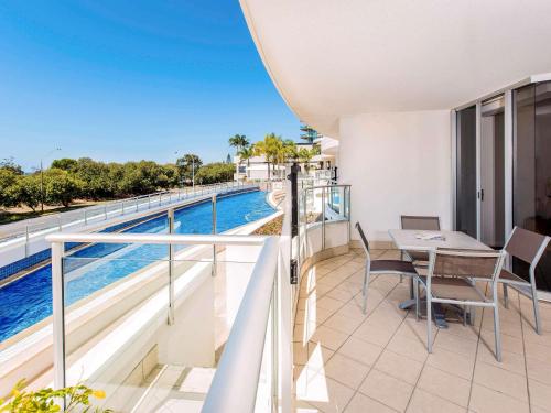 a balcony with a table and chairs and a swimming pool at The Sebel Maroochydore in Maroochydore