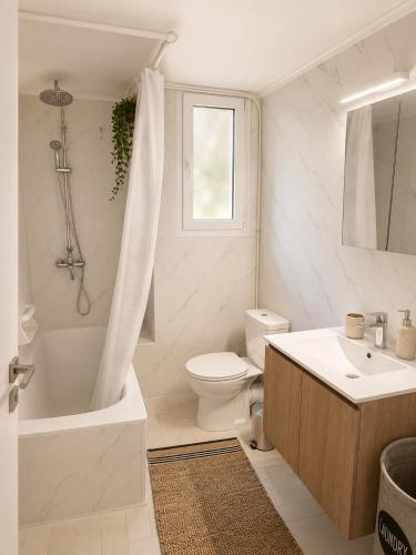 a white bathroom with a toilet and a tub and a sink at Aggelina's Apartment in Zakynthos