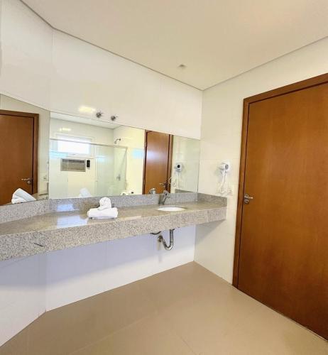 a bathroom with a sink and a large mirror at Orla Morena Park Hotel in Campo Grande