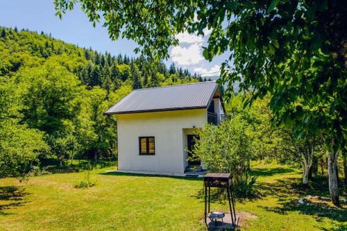 a small white house in the middle of a field at River Valley Guest House in Foča