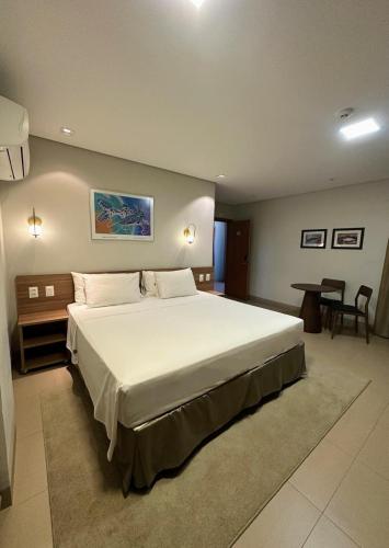 a bedroom with a large bed and a table at Orla Morena Park Hotel in Campo Grande
