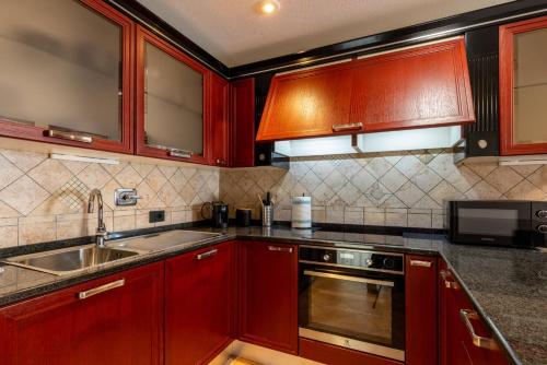 a kitchen with red cabinets and a sink and a microwave at Aosta Centre Apartments - Santo Stefano in Aosta