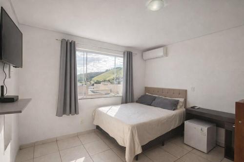 a small bedroom with a bed and a window at Pousada Lagus Pan in Capitólio