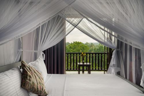 a bedroom with a bed and a balcony with a window at Sri Yoga Shala in Unawatuna