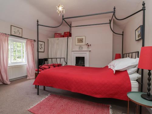 a bedroom with a red bed and a fireplace at Wolvesacre Mill Cottage in Whitchurch