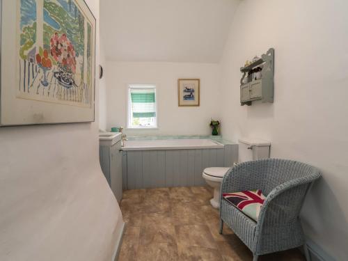 a bathroom with a toilet and a chair at Wolvesacre Mill Cottage in Whitchurch