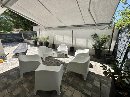 a patio with white chairs and tables and a canopy at ZR9 in Zamárdi