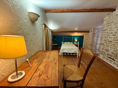 a room with a table with a bed and a lamp at Chambre d'hôtes Les Bleuets in Melle