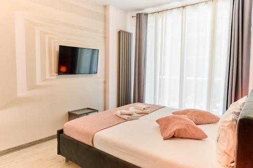 ein Schlafzimmer mit einem Bett und einem Fernseher an der Wand in der Unterkunft Bavaro 28 by Alezzi Resort in Mamaia Nord – Năvodari
