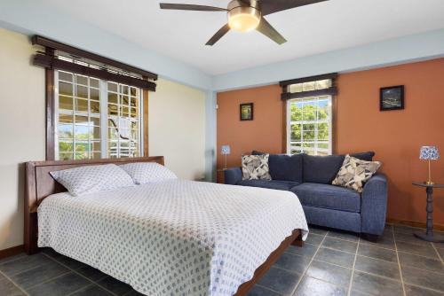 a bedroom with a bed and a couch and a ceiling fan at The Ceiba Villa by Otium in Aguas Claras