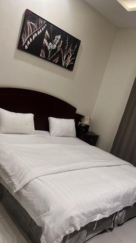 a bedroom with a large bed with white sheets at شقق فندقية 2 in Buraydah
