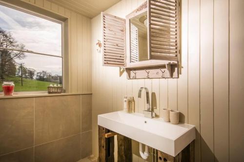 a bathroom with a white sink and a window at Sunbank Yurt in Llangollen