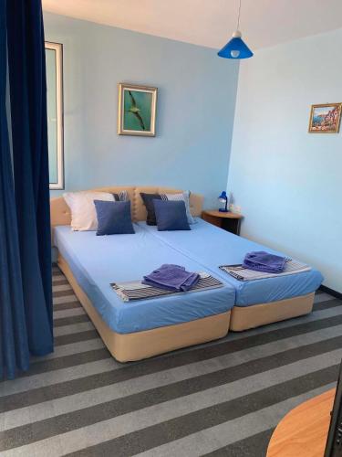 a bedroom with a large bed with blue sheets at Мирели in Ravda