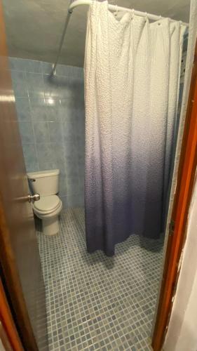 ein Badezimmer mit Toilette und Duschvorhang in der Unterkunft Corazón Abierto in Chicxulub