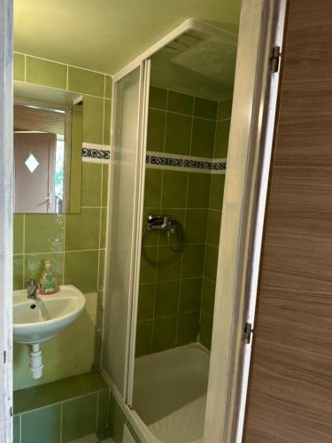 a green tiled bathroom with a sink and a shower at Apartmán Gál 2 in Kvačany