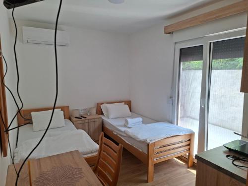 a room with two beds and a table and a window at Apartmani Jet Set in Bor