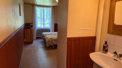 a bathroom with a sink and a bedroom with a bed at Skagagården-peaceful stay near Tiveden National Park in Undenäs