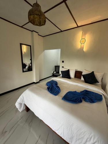 a bedroom with a large white bed with blue pillows at Hill Nest Ella in Bandarawela