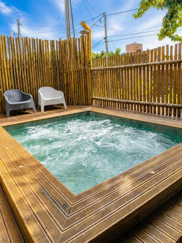 a swimming pool with two chairs and a wooden fence at Pousada Divino Milagre in Passo de Camarajibe