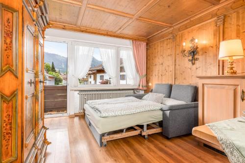 a bedroom with a bed and a couch and a window at Landhaus Pichler mit Sauna in Ruhpolding