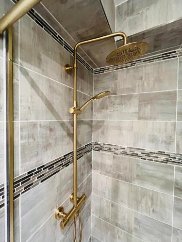 a shower with a gold shower head in a bathroom at Le Faubourg St Martin Gold&Green in Senlis