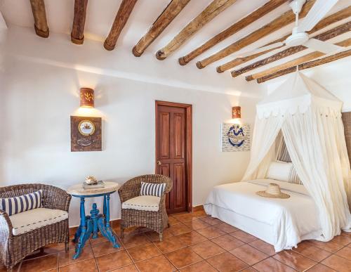 a bedroom with a bed and two chairs and a table at Ser Casasandra Boutique Hotel in Holbox Island