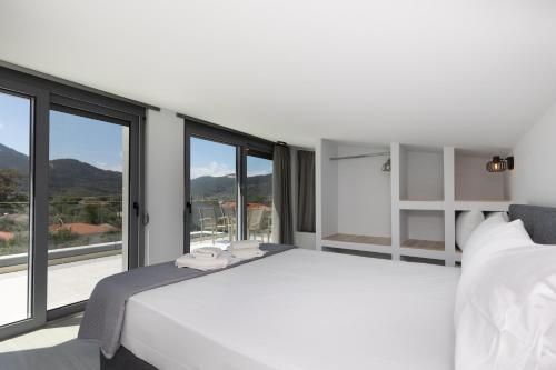 a white bedroom with a large bed and large windows at Verde Villas in Skala Potamias