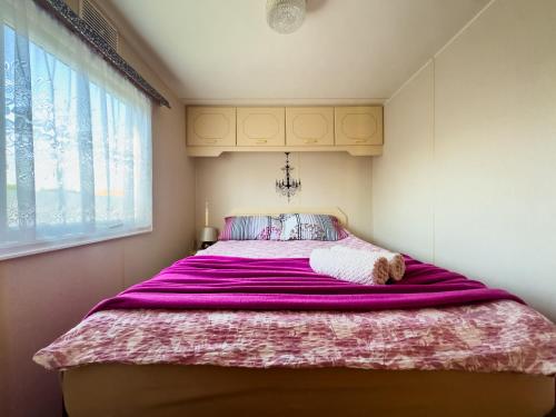 a bedroom with a large bed with a purple blanket at Motyl in Doba
