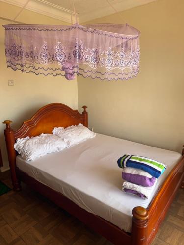 a bedroom with a bed with white sheets and pillows at Crown Motel Lugala in Kampala