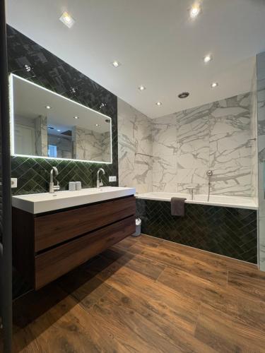a bathroom with a sink and a tub and a mirror at Mariposa in Otterlo