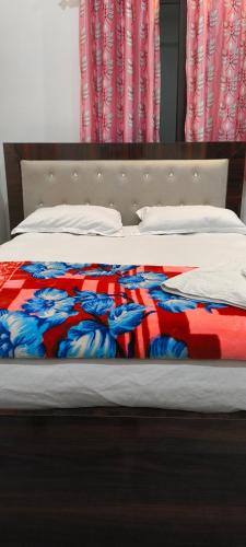 a bed with a red and blue blanket on it at Hotel Purvanchal in Katihār