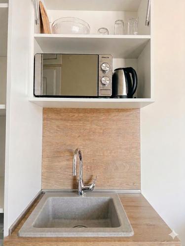 a sink in a kitchen with a microwave above it at Hotel ADMIRAL POTOS THASSOS in Potos