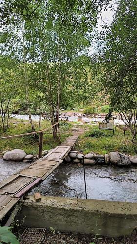 a wooden bridge over a stream in a park at Дача in Bishkek